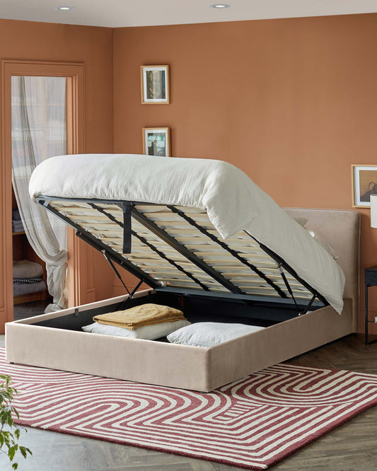 A stylish beige storage bed with an elevated mattress revealing hidden compartment for bedding, set on a patterned rug.