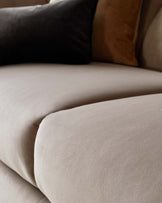 Plush beige sofa featuring soft fabric and layered cushions in black and warm tones for a cozy, inviting look.