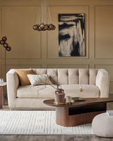 Elegant beige sofa with tufted details, modern coffee table, textured rug, stylish pendant lighting, and decorative accents.