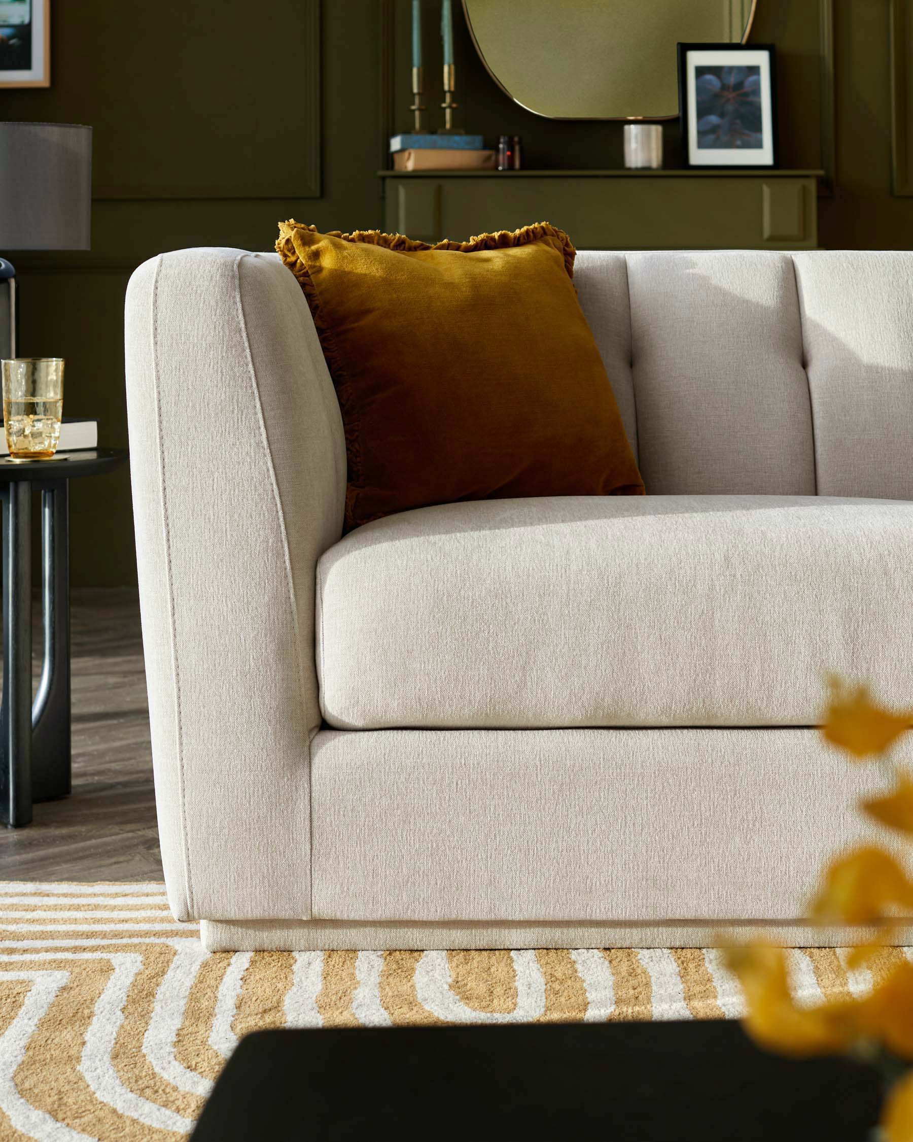 Neutral-toned sofa with tufted detailing, complemented by a mustard throw pillow, and paired with a modern side table.