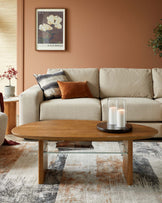 Cozy beige sofa with patterned cushions, modern oval wooden coffee table, and decorative candles on a chic rug.