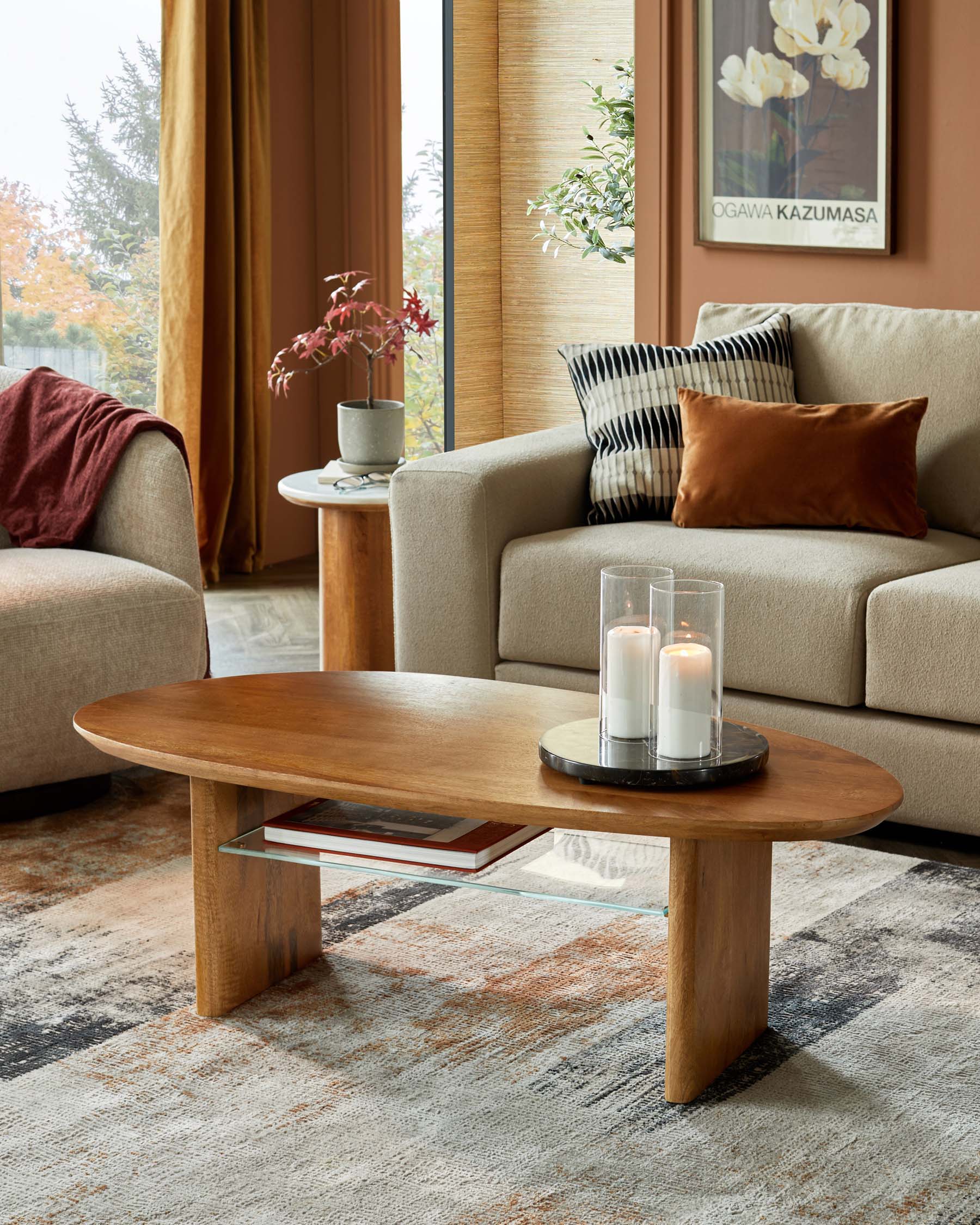 Modern living room features a beige sofa, wooden oval coffee table with glass shelf, and decorative candles on a circular tray.