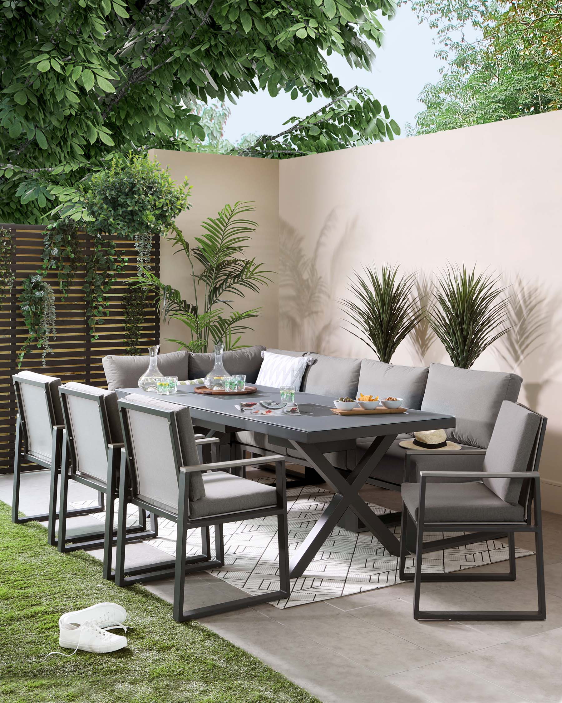 Contemporary outdoor dining set featuring a rectangular table with a sleek, dark grey finish and a distinctive X-shaped base. The set includes six matching chairs with clean lines, dark frames, and contrasting light grey cushioned seats and backrests for comfortable seating. The ensemble is arranged on a patio with decorative greenery in the background, creating an inviting space for outdoor gatherings.