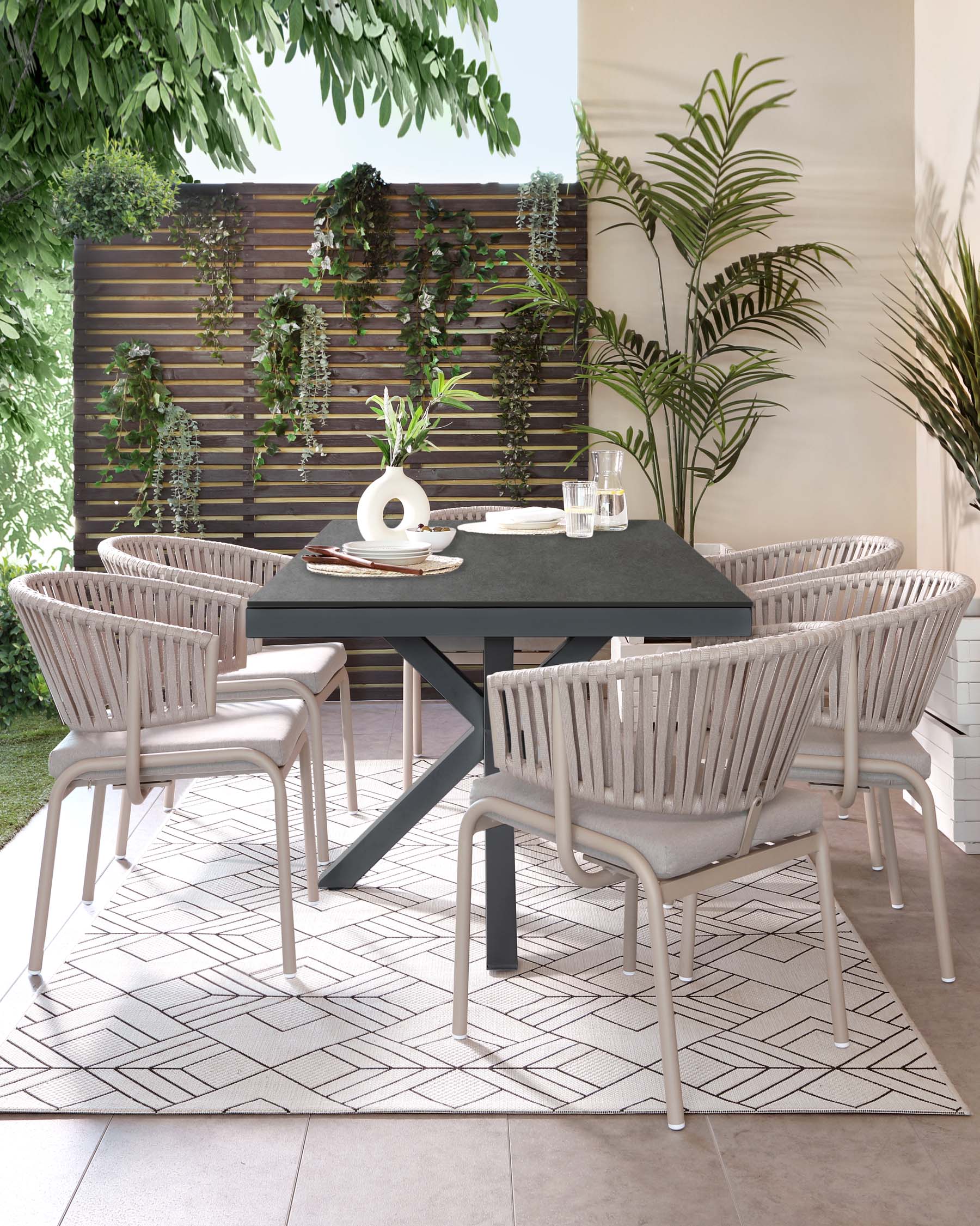 Contemporary outdoor dining set featuring four stylish light grey, woven rope chairs with metal legs and cushioned seats, paired with a minimalist black rectangular table with a solid top and angular metal legs. The set is arranged on a geometric-patterned outdoor rug, complementing an elegant patio setting.