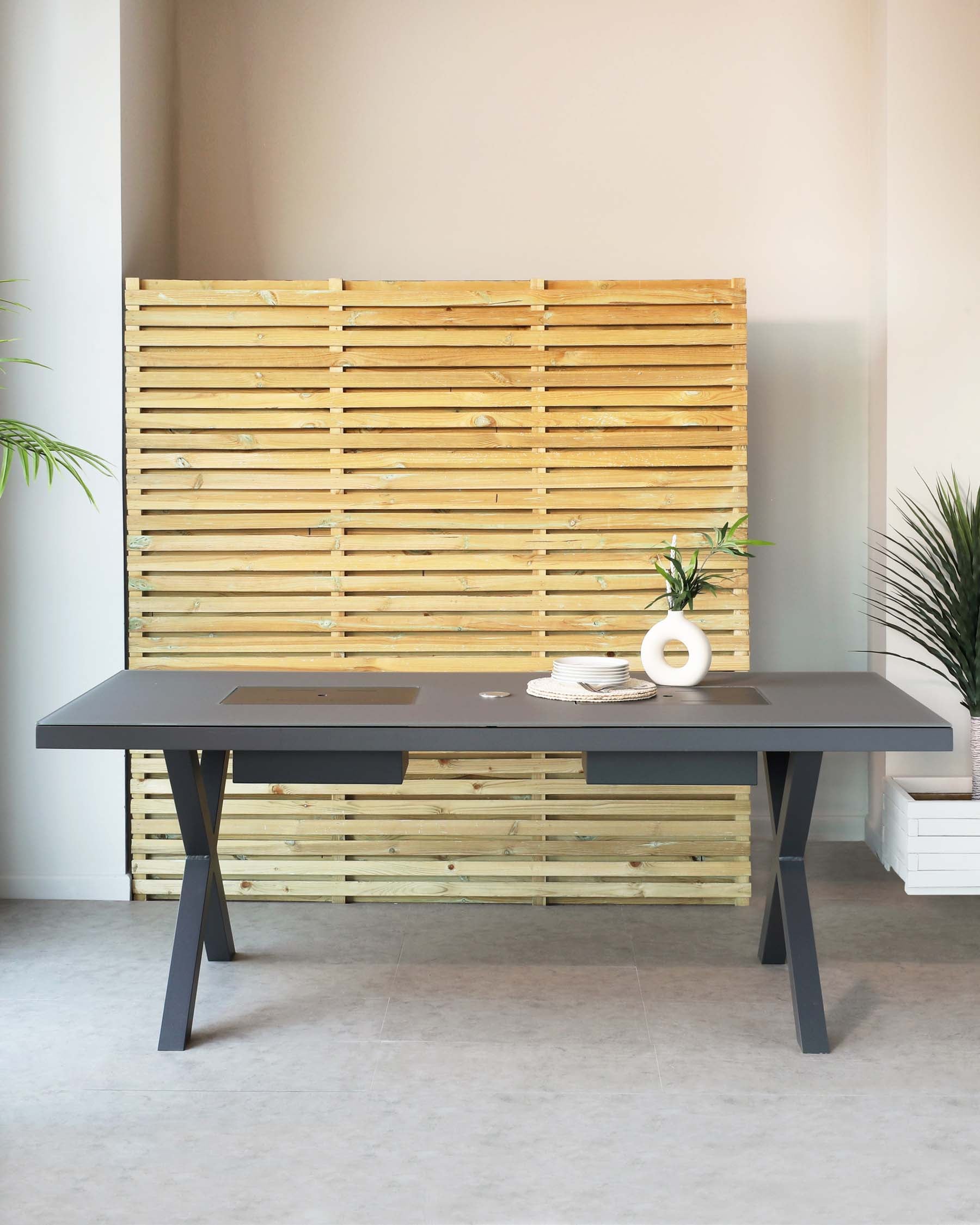 Modern minimalist dining table in matte black with clean lines and angular metal legs, set against a natural wood slatted backdrop.