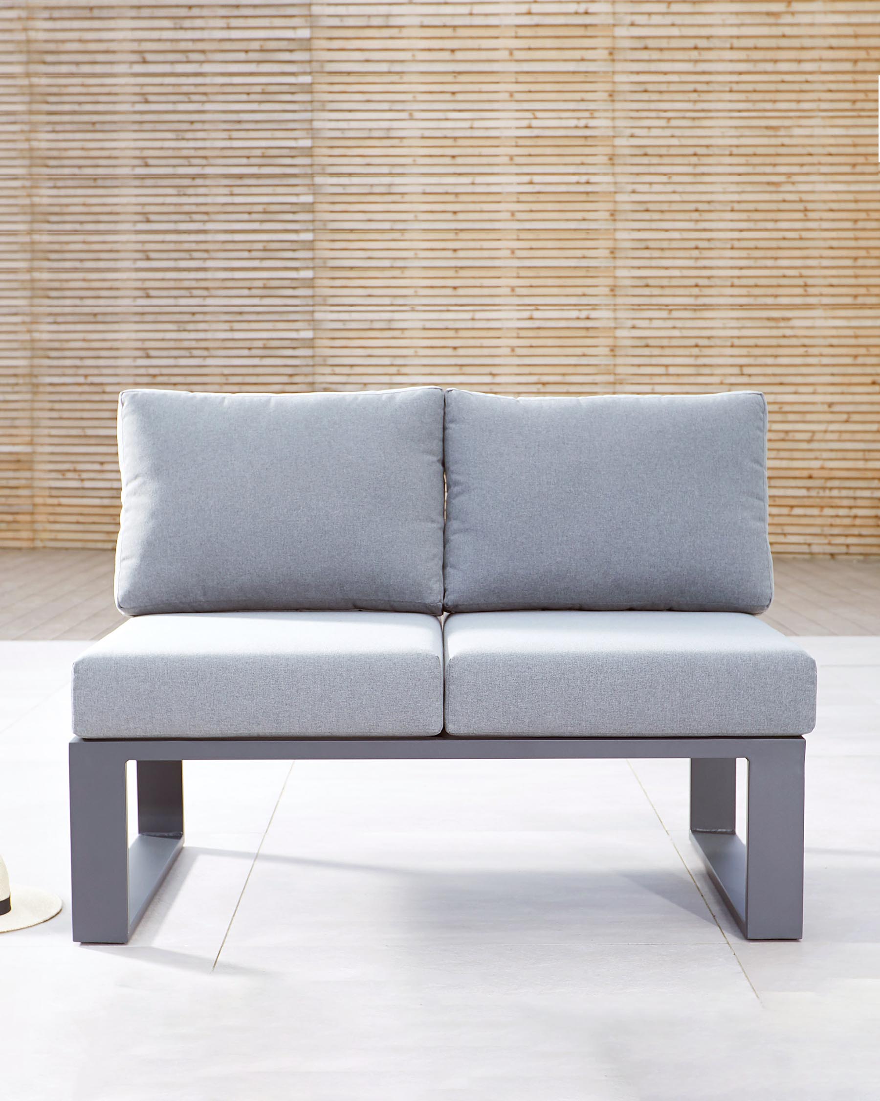 Modern outdoor two-seater sofa with light grey cushions on a minimalist dark grey metal frame, set against a bamboo backdrop.