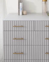 Elegant modern grey dresser with gold horizontal handles and a textured front consisting of overlapping, wavy ridges.