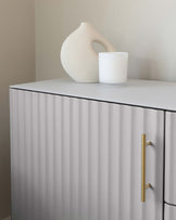 Modern minimalist-style sideboard with vertical fluted detailing and metallic gold handles.