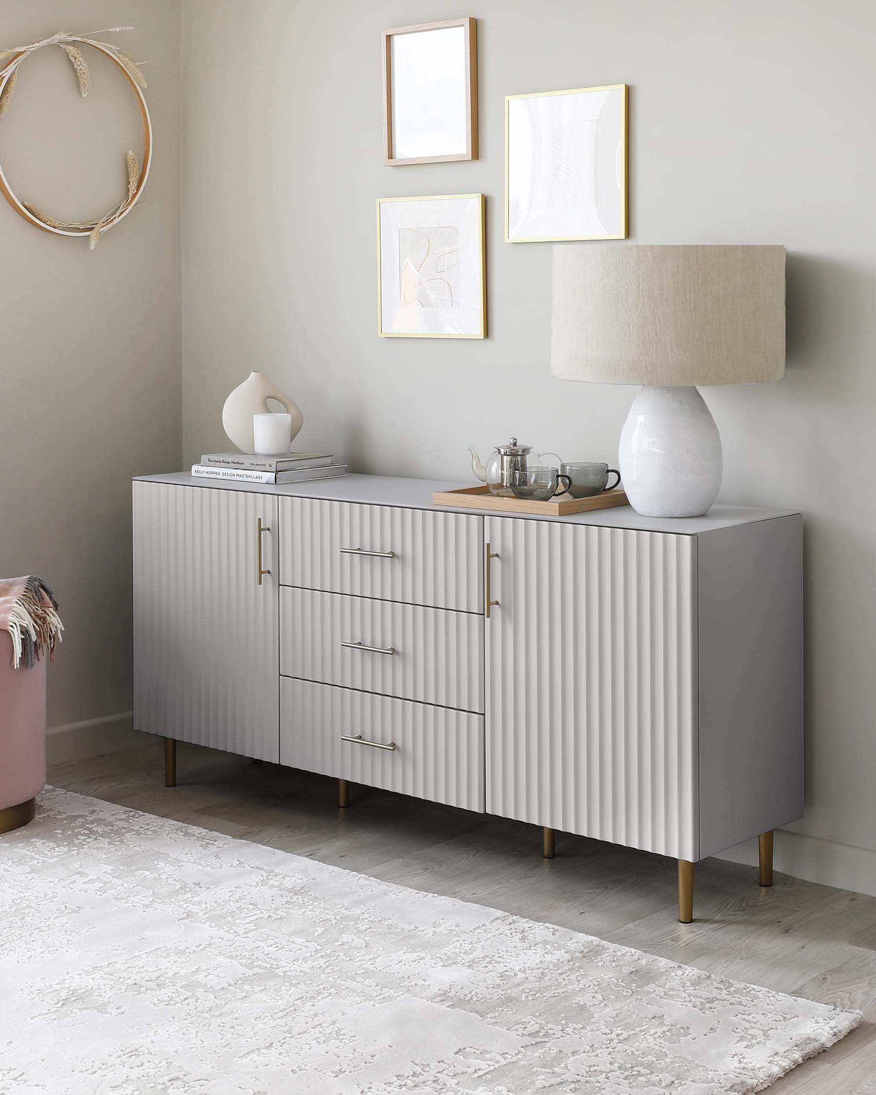 Modern light grey sideboard featuring fluted front panels and gold-finished metal handles, supported by conical wood legs with gold-finished tips, set against a neutral wall.