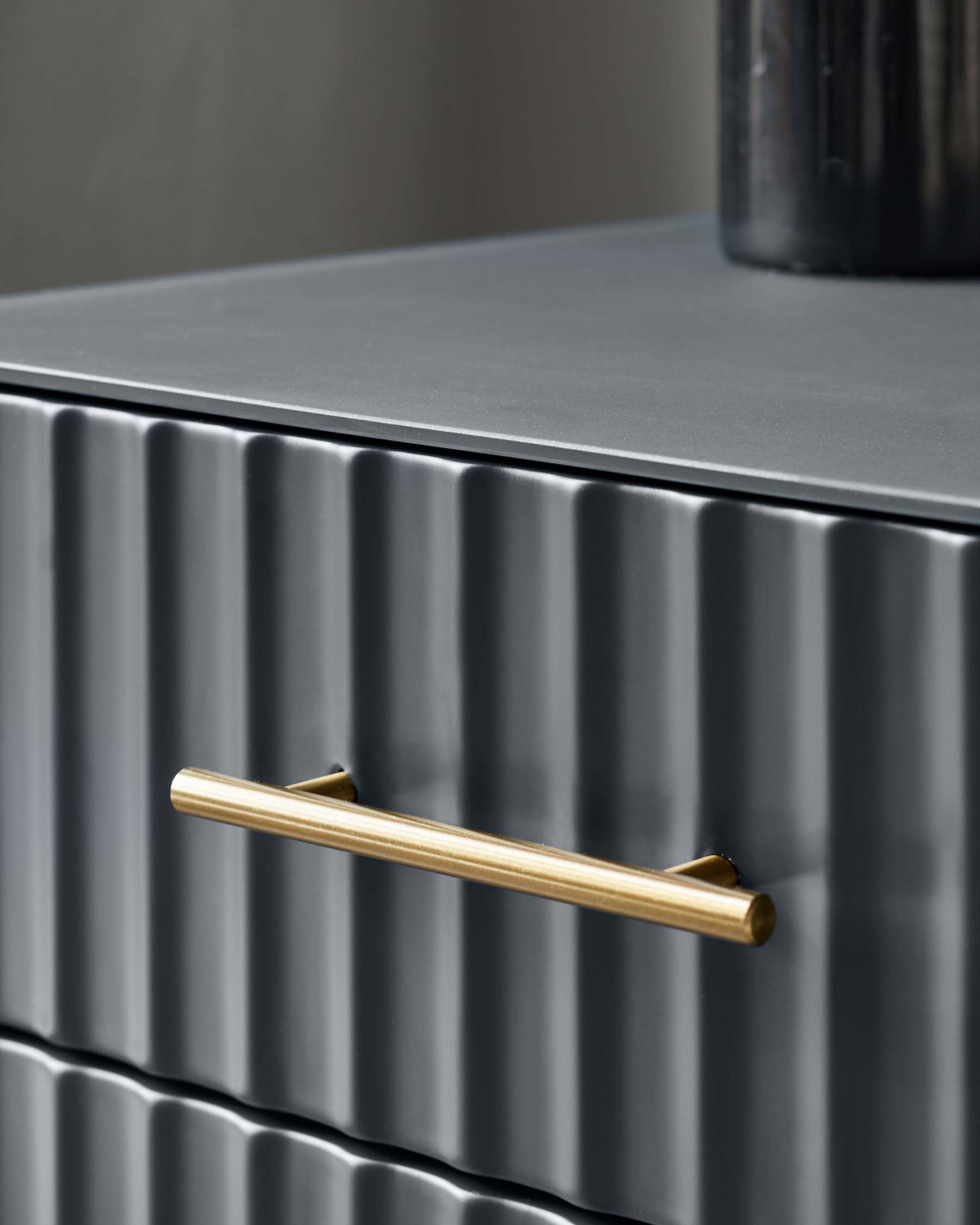 Contemporary dark grey chest of drawers featuring a textured vertical rib design and a brushed gold metal handle.