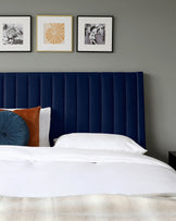 Navy upholstered headboard with vertical stripes, accented by decorative cushions in teal and rust, against a neutral wall.