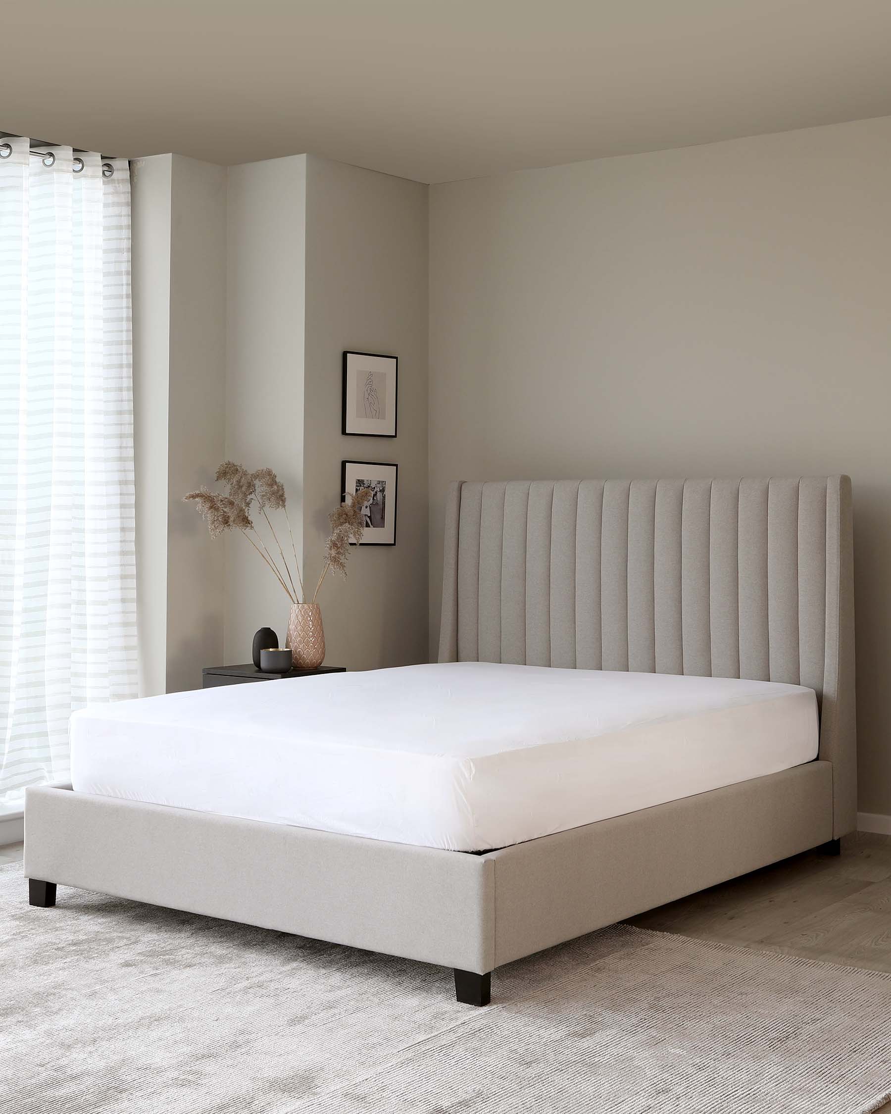 Modern minimalist style bedroom with a large beige upholstered bed featuring a vertical channel-tufted headboard and a coordinating platform base, set on a textured grey area rug.