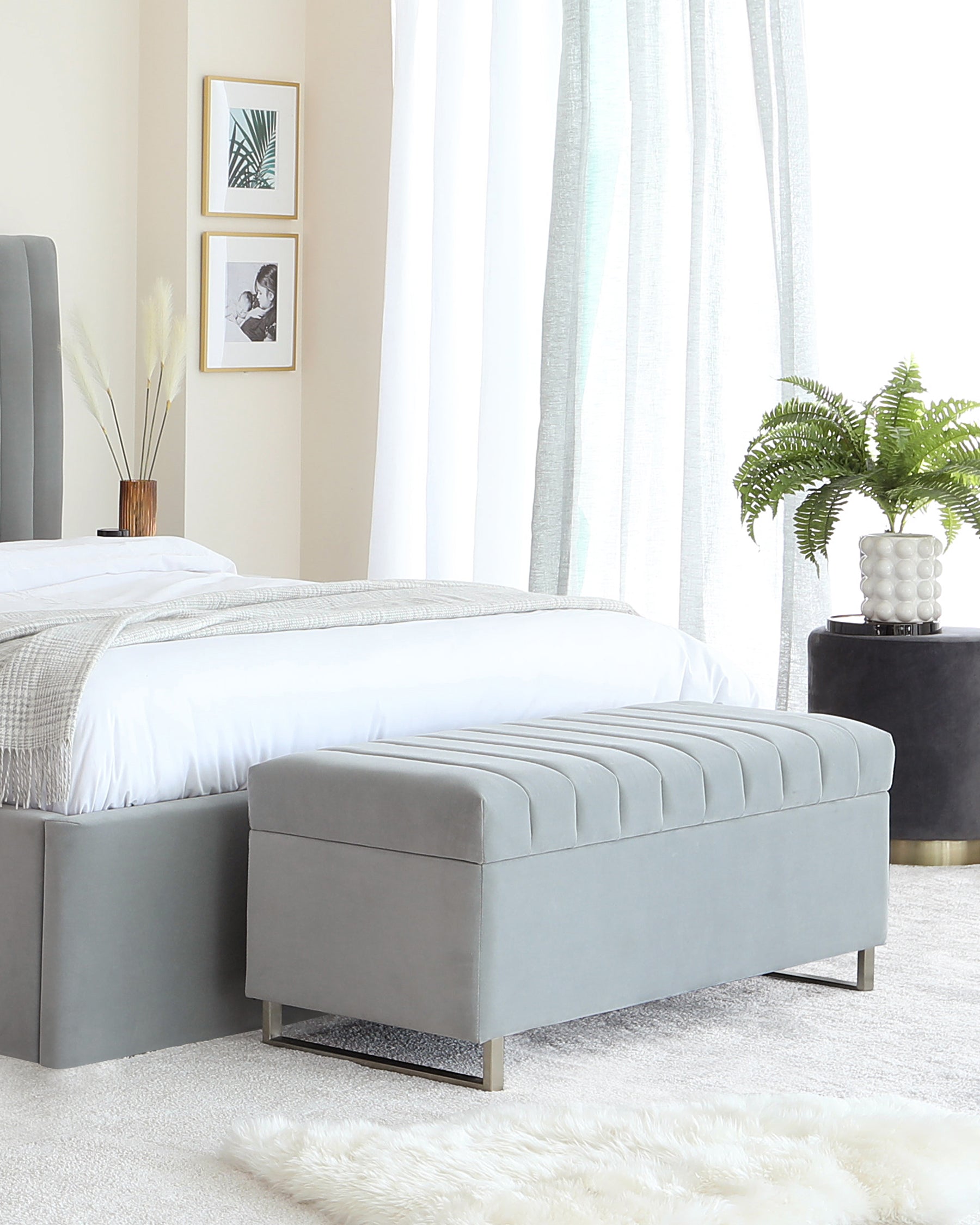 Modern bedroom furniture set including an upholstered platform bed with a tufted headboard in a soft grey colour and a matching tufted storage bench at the foot of the bed. Both pieces stand on sleek, metallic legs, creating a contemporary and stylish look.