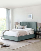 A stylish bedroom featuring a teal upholstered bed with a vertically channelled headboard and a matching bed frame. Beside the bed, there is a contemporary black nightstand with a lamp and decorative vase atop. The furniture is showcased on a neutral area rug, creating an elegant and serene atmosphere.