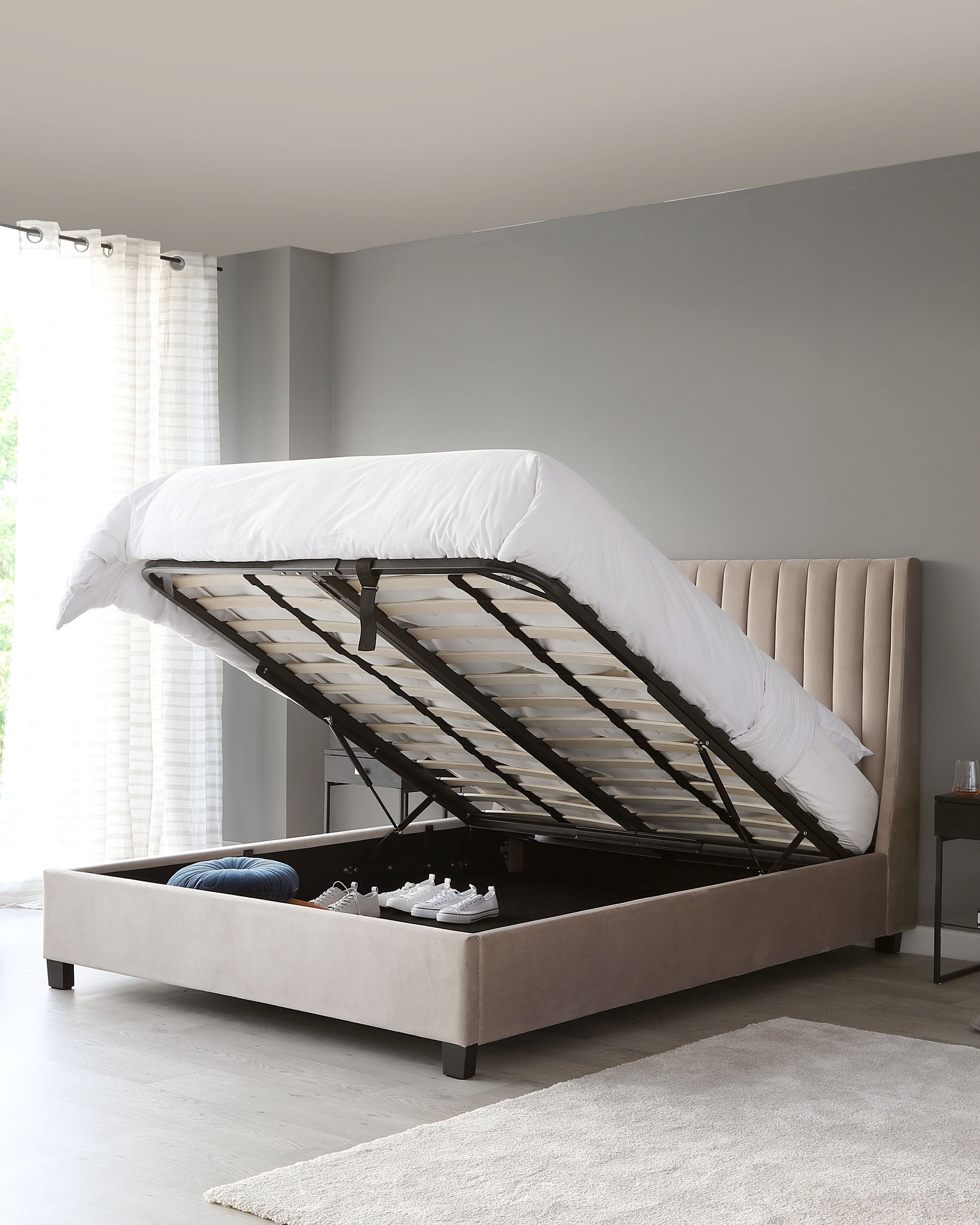 Contemporary taupe upholstered storage bed with a tufted headboard design and a gas-lift mechanism revealing under-bed storage space.