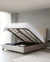 Contemporary beige upholstered storage bed with a tufted headboard design, featuring a gas-lift mechanism to access the under-bed storage compartment.