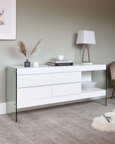 Modern white sideboard with sleek drawers and black metal accents, featuring an integrated shelf space on the right. The piece is styled with a table lamp, decorative books, a vase with dried pampas grass, and a modern textured bowl.