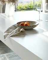 A minimalist white dining table with a clean, sleek finish and a rectangular top, positioned in a well-lit room with natural light.