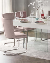 A modern dining set featuring a white rectangular table with a glossy finish and clear glass legs. Accompanied by four blush pink velvet upholstered chairs with unique curving chrome metal base, set on a textured off-white area rug.