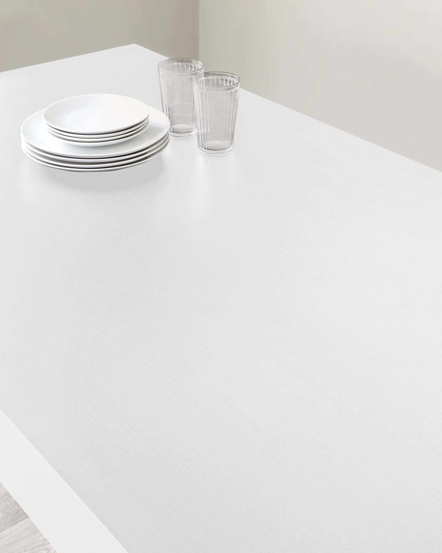 A modern minimalist white dining table with a smooth top and clean lines, set against a neutral background.