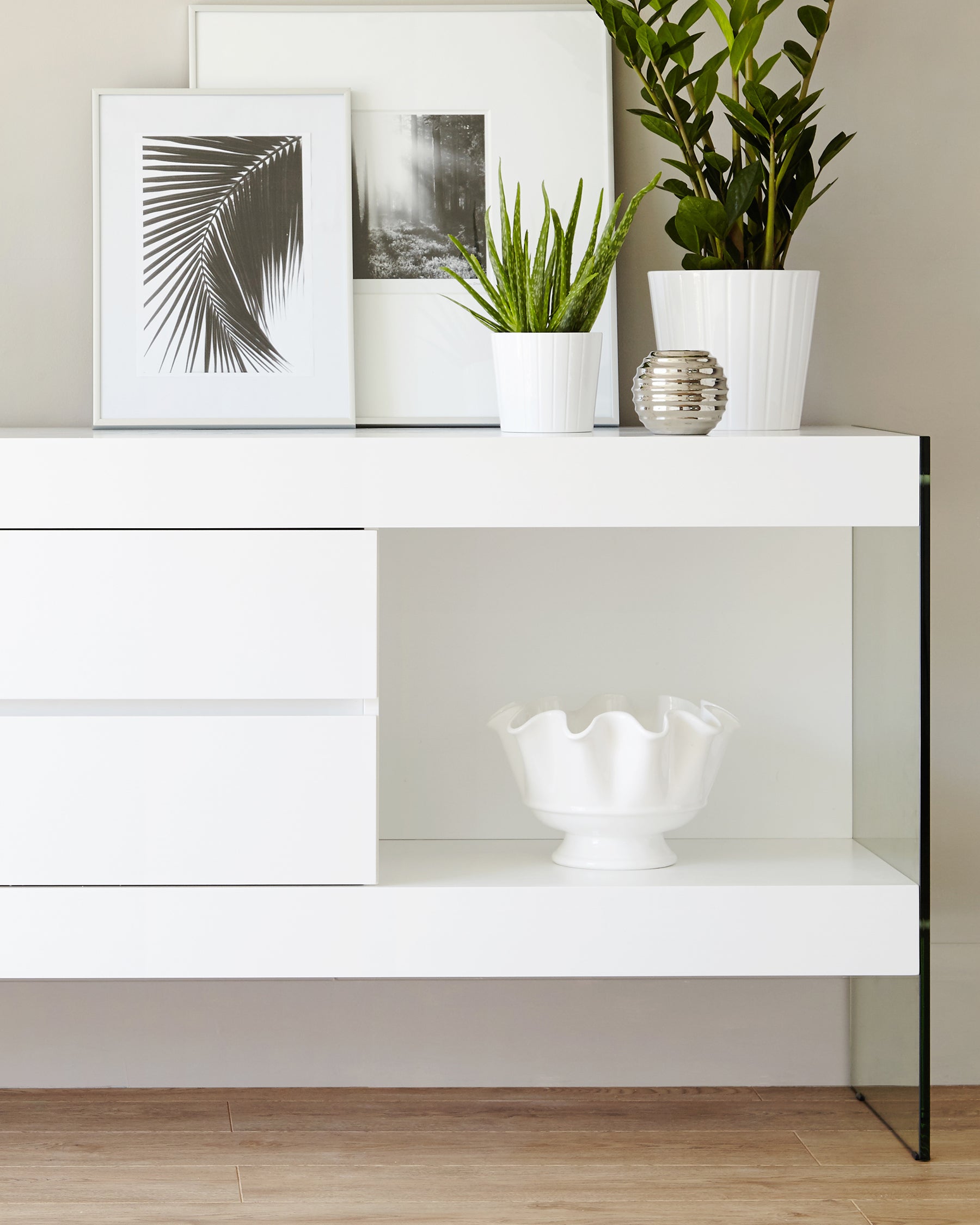 Modern white console table with clean lines featuring two drawers and one open shelf. The console has a minimalist design with black metal accents on the legs.