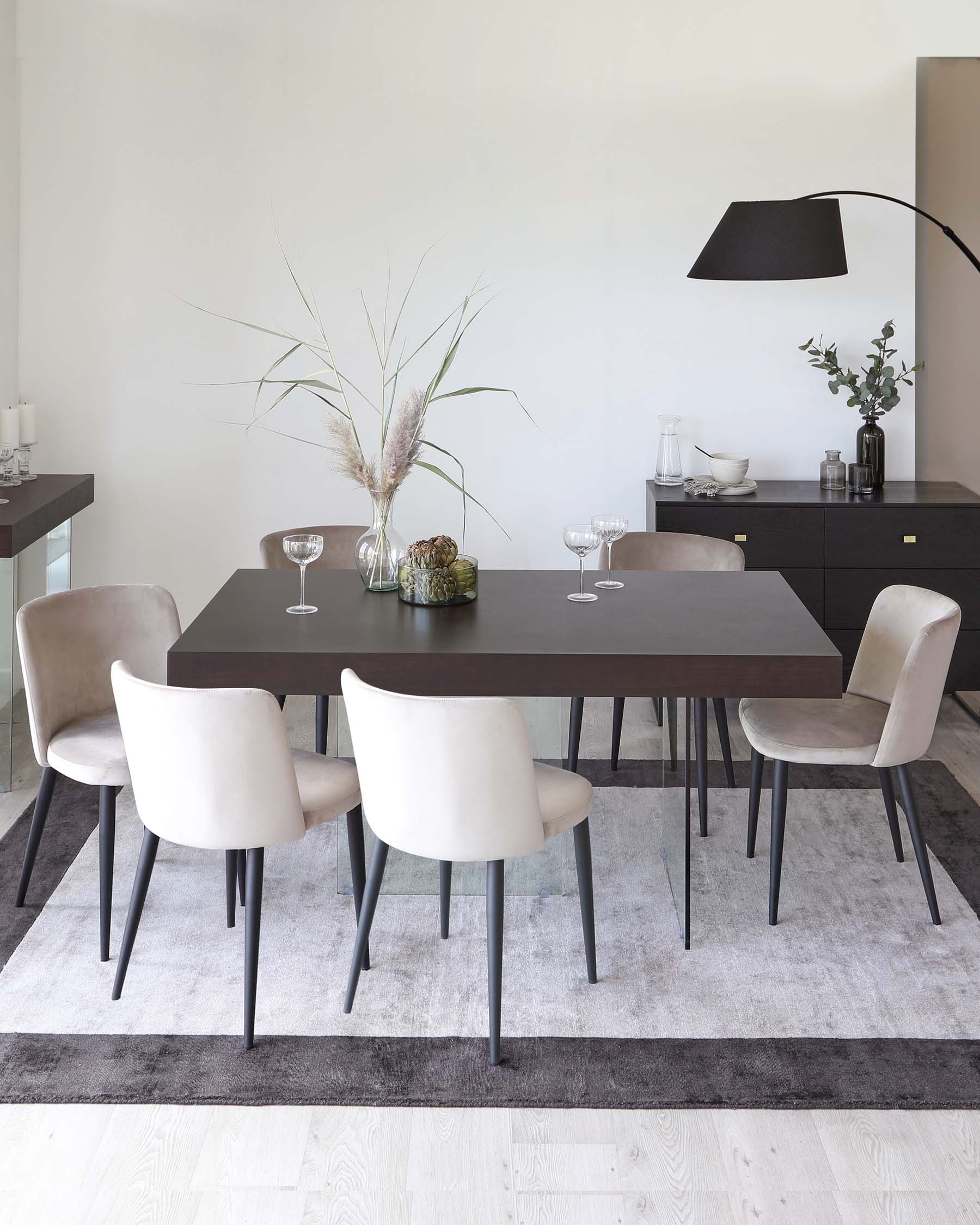 Modern dining room set including a dark brown rectangular table and six beige upholstered chairs with black legs, arranged on a grey ombre area rug. A black sideboard with brass handles is placed against the wall, complemented by a black floor lamp with an oversized shade extending over the table.