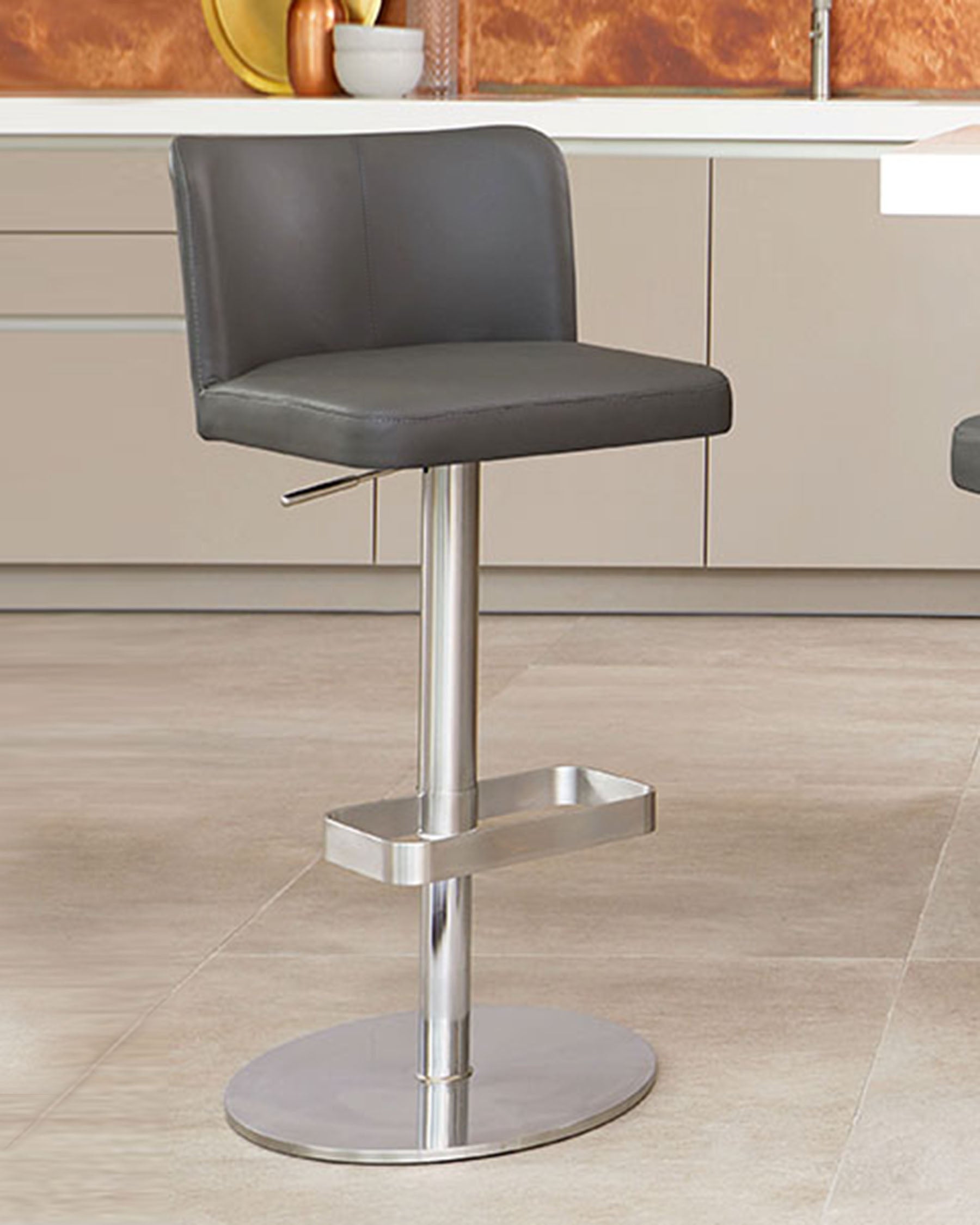 Modern adjustable bar stool with a chrome pedestal base, integrated footrest, and a sleek black leatherette seat with a low backrest.