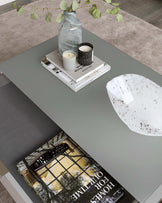 Modern rectangular coffee table in a matte grey finish, featuring clean lines and a minimalist design. The tabletop is accessorized with a decorative vase, candles, a tray, and a book, suggesting a contemporary and cosy living space.