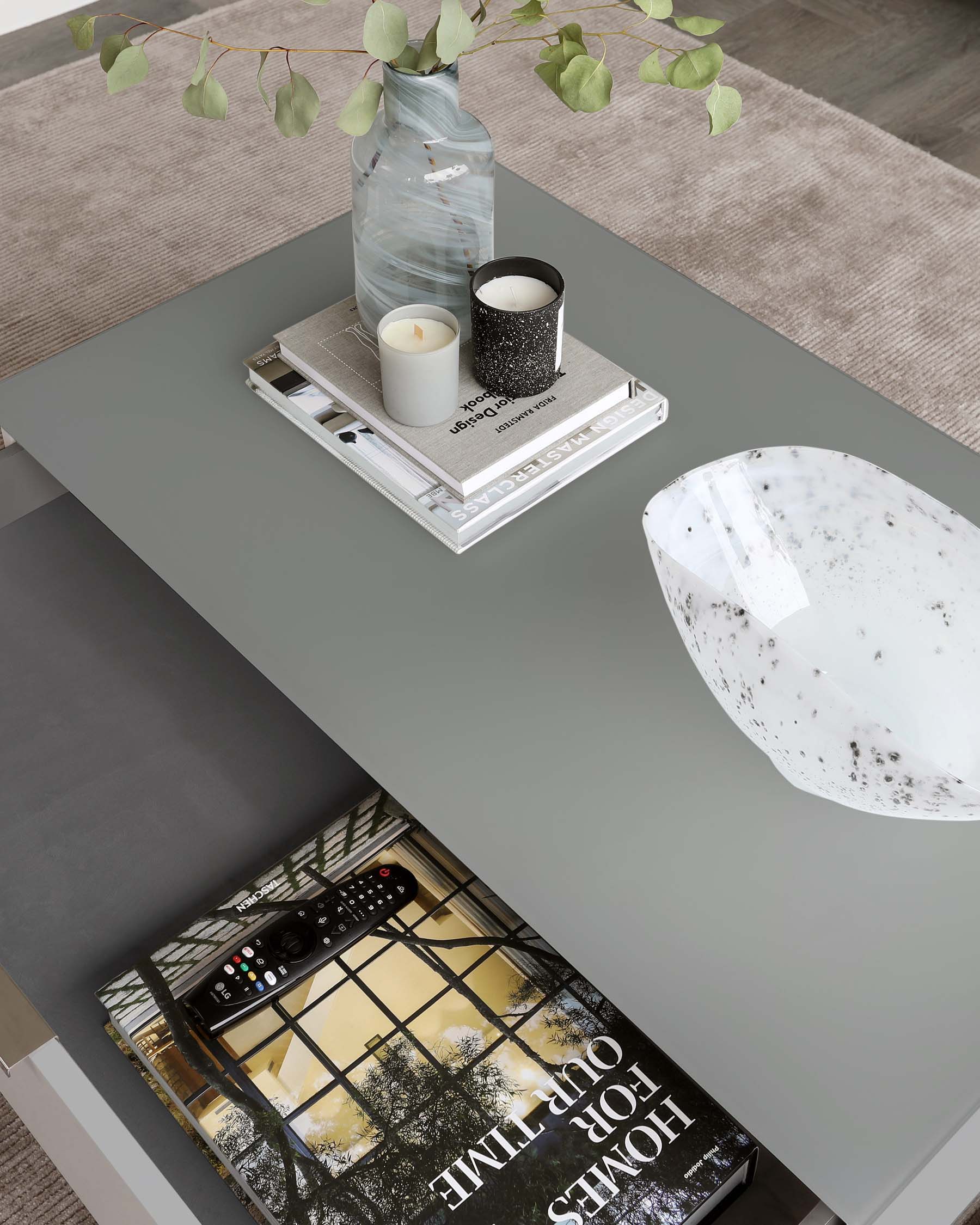 Modern rectangular coffee table in a matte grey finish, featuring clean lines and a minimalist design. The tabletop is accessorized with a decorative vase, candles, a tray, and a book, suggesting a contemporary and cosy living space.