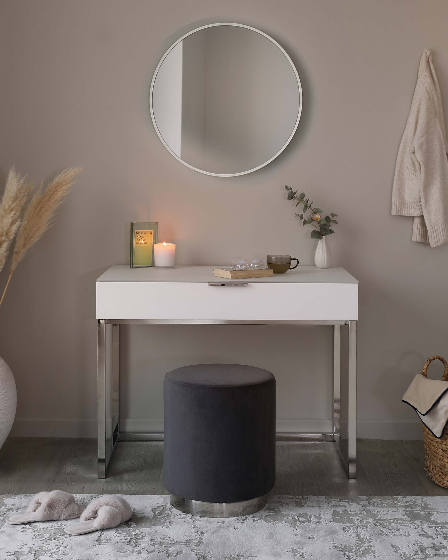 Modern minimalist white console table with metal legs and a round upholstered grey ottoman with a metal base.