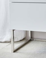 Modern minimalist white cabinet with sleek lines and metal legs.