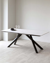 Modern rectangular dining table with a white marble top and angular black metal legs in a minimalist interior setting.