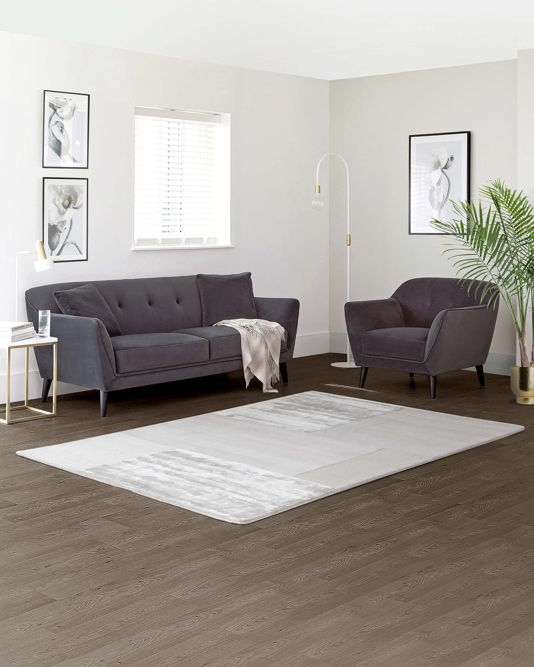 Modern living room furniture set featuring a dark grey fabric three-seater sofa with tufted backrest and two matching armchairs, complemented by a white marble-top side table with gold metal frame. A plush white and grey area rug anchors the arrangement on a dark hardwood floor.