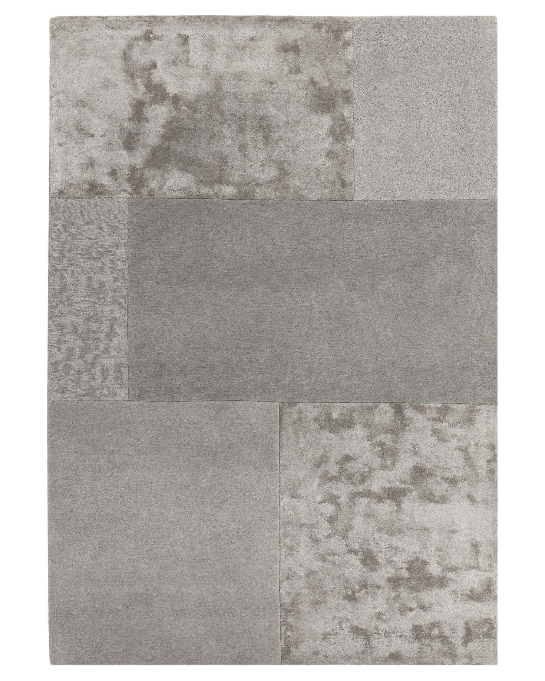 Contemporary area rug featuring an asymmetrical patchwork design with varying shades of grey, including solid blocks and a textured, marbled pattern.