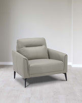 Contemporary light grey upholstered armchair with sleek lines, angled black legs, and plush seating, positioned on a light wood floor against a plain white wall.