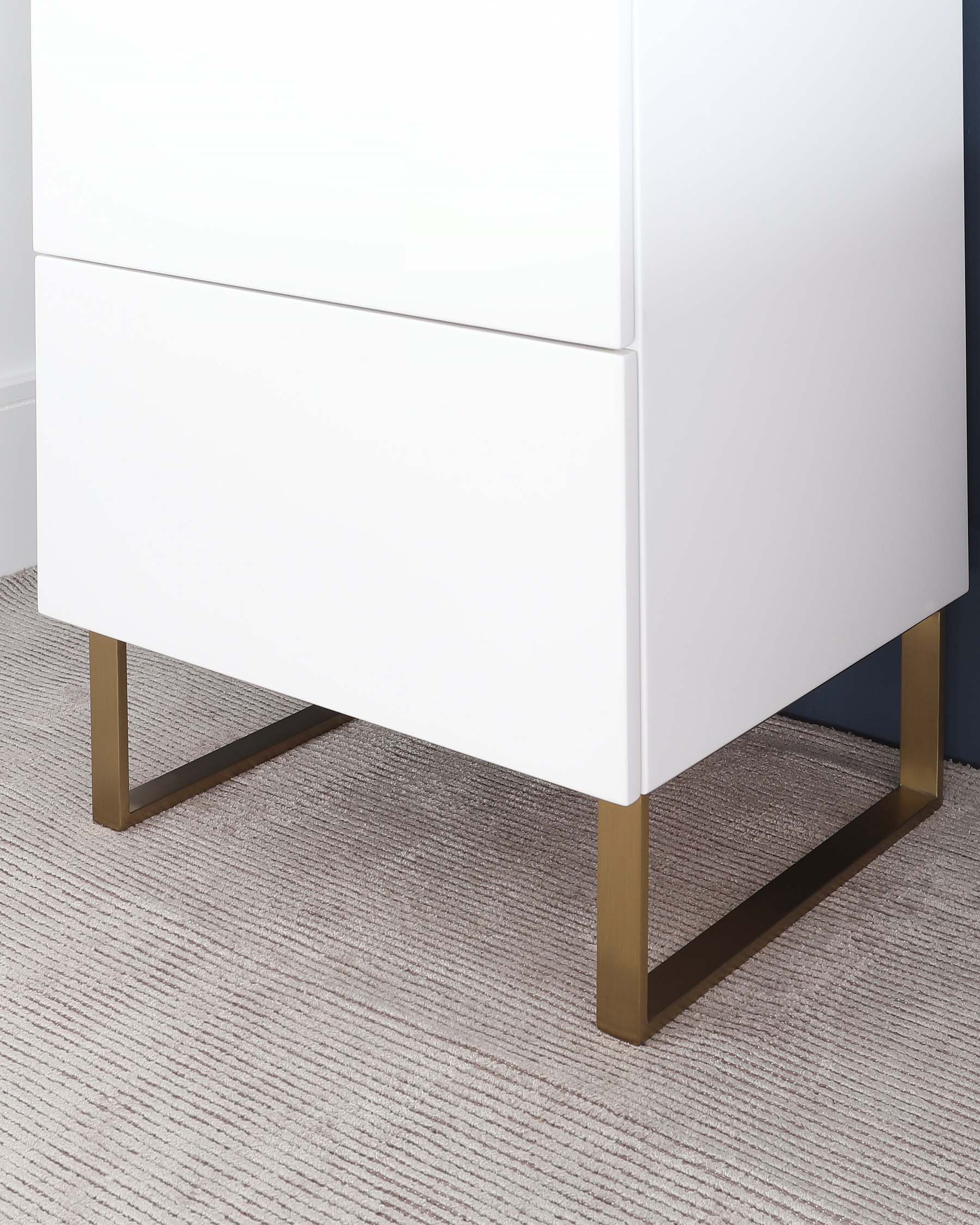 Modern white two-drawer nightstand with sleek no-handle design and angled, brushed gold metal legs.