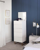 Modern white tallboy dresser with six drawers, featuring a sleek handle-less design, a contrasting wooden base with angled legs, and an attached vertical mirror.