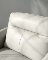 Close-up view of a modern, off-white leather sofa, showing detail of the plush cushioning and fine-grain leather texture, with an emphasis on its luxury design and comfort.