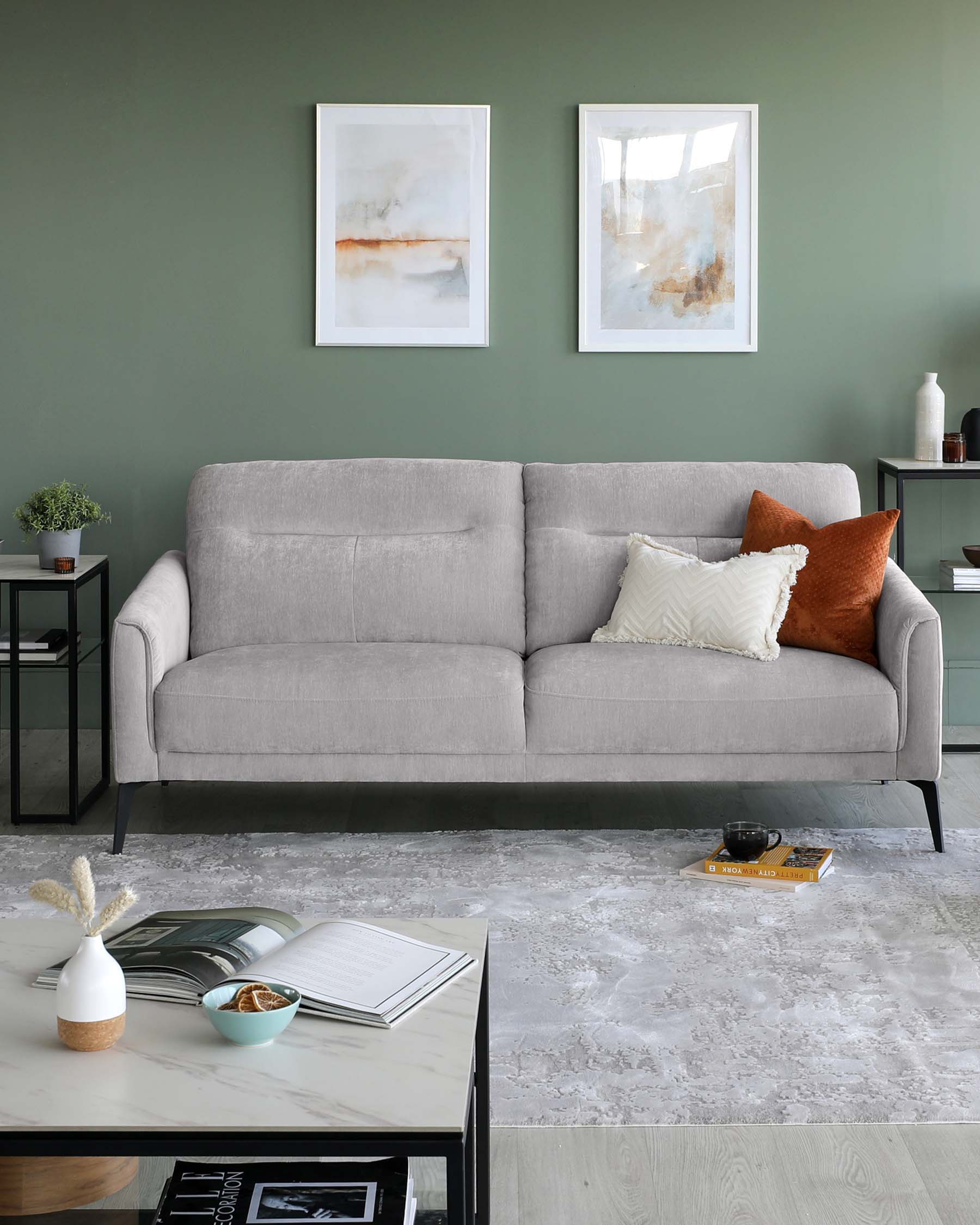 Modern three-seater sofa with light grey upholstery and black metal legs, accompanied by a marble-top coffee table with black metal frame and two-tier side table with black metal body and glass tops.