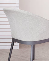 Modern chair with a curved backrest upholstered in a textured light grey fabric, featuring a sleek dark grey metallic frame with slender legs.