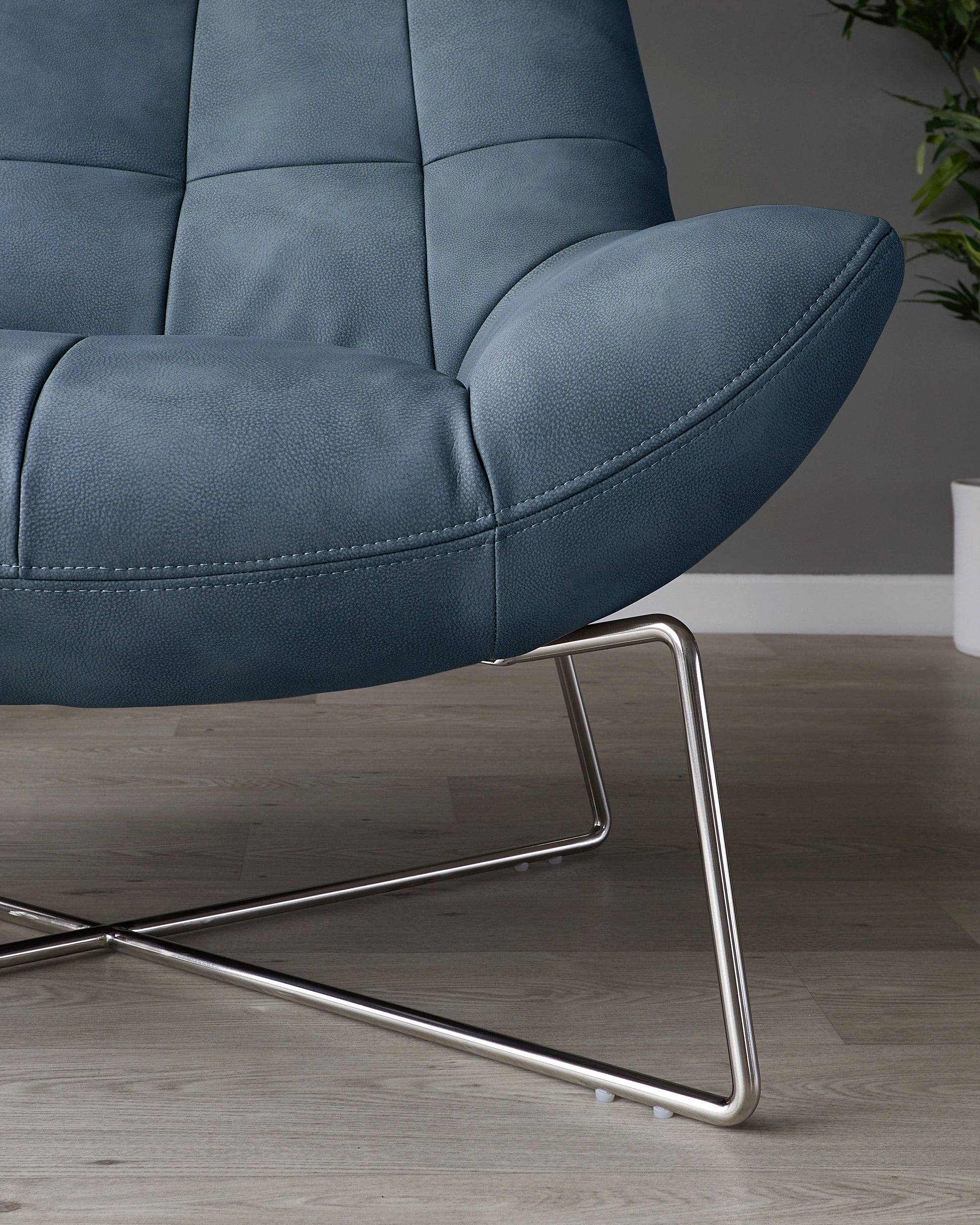 Modern blue upholstered armchair with a tufted backrest and a unique metallic X-shaped base.