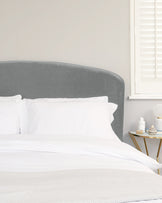 Elegant bedroom with a contemporary upholstered grey headboard, white bedding, and a modern gold and glass side table.