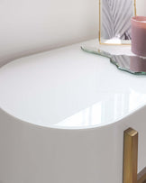 White modern curved console table with a sleek surface and golden cylindrical legs.