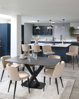 Modern dining room featuring a sleek, black oval table with a distinctive X-shaped base and a set of six beige upholstered chairs with slim, black metal legs. The elegant yet functional design creates a stylish and welcoming eating area.