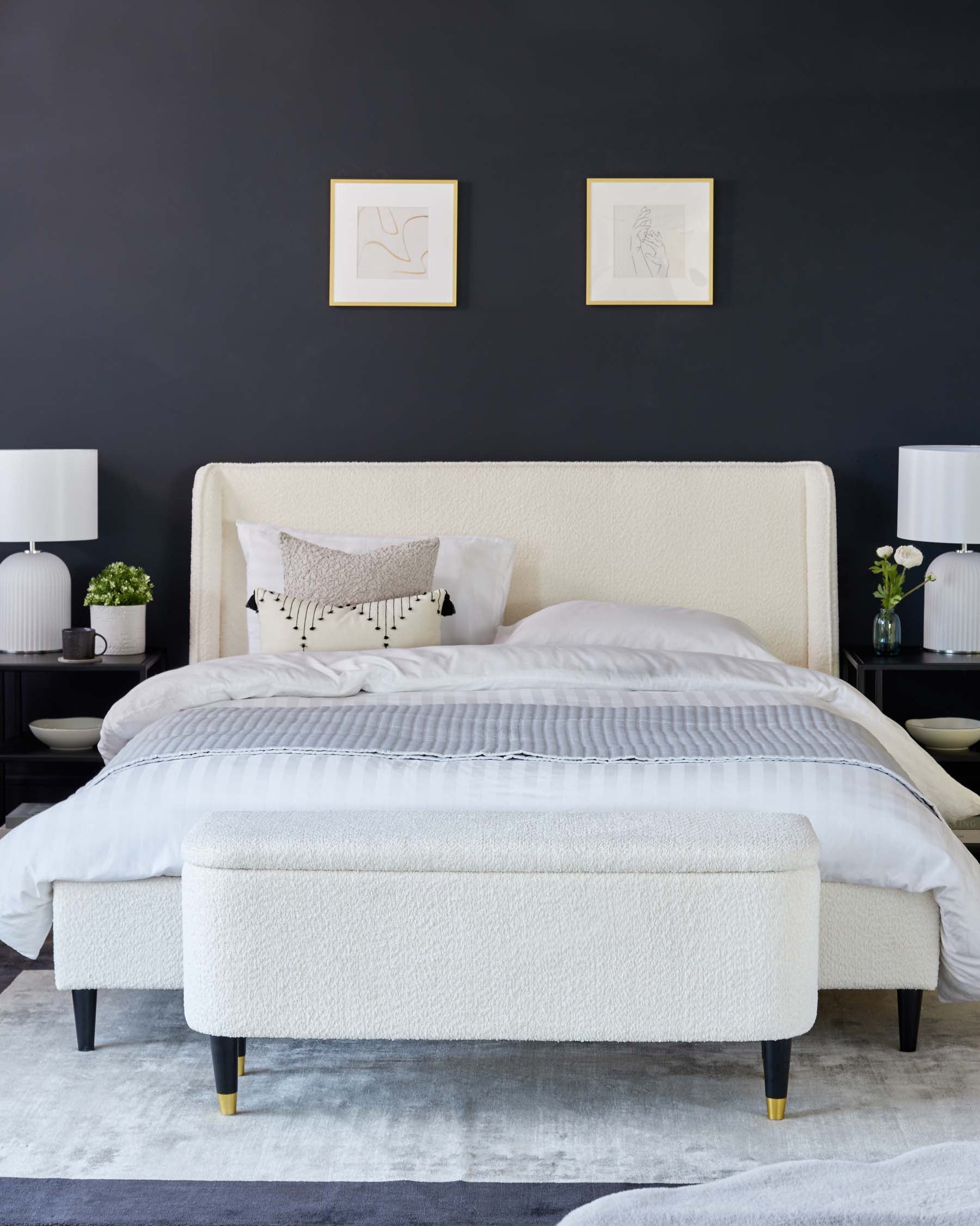 Elegant contemporary bedroom furniture set featuring an upholstered queen-size bed with a textured cream headboard and matching bench at the foot, both with black legs that include brass cap accents. A plush grey area rug underlies the bed and bench ensemble.