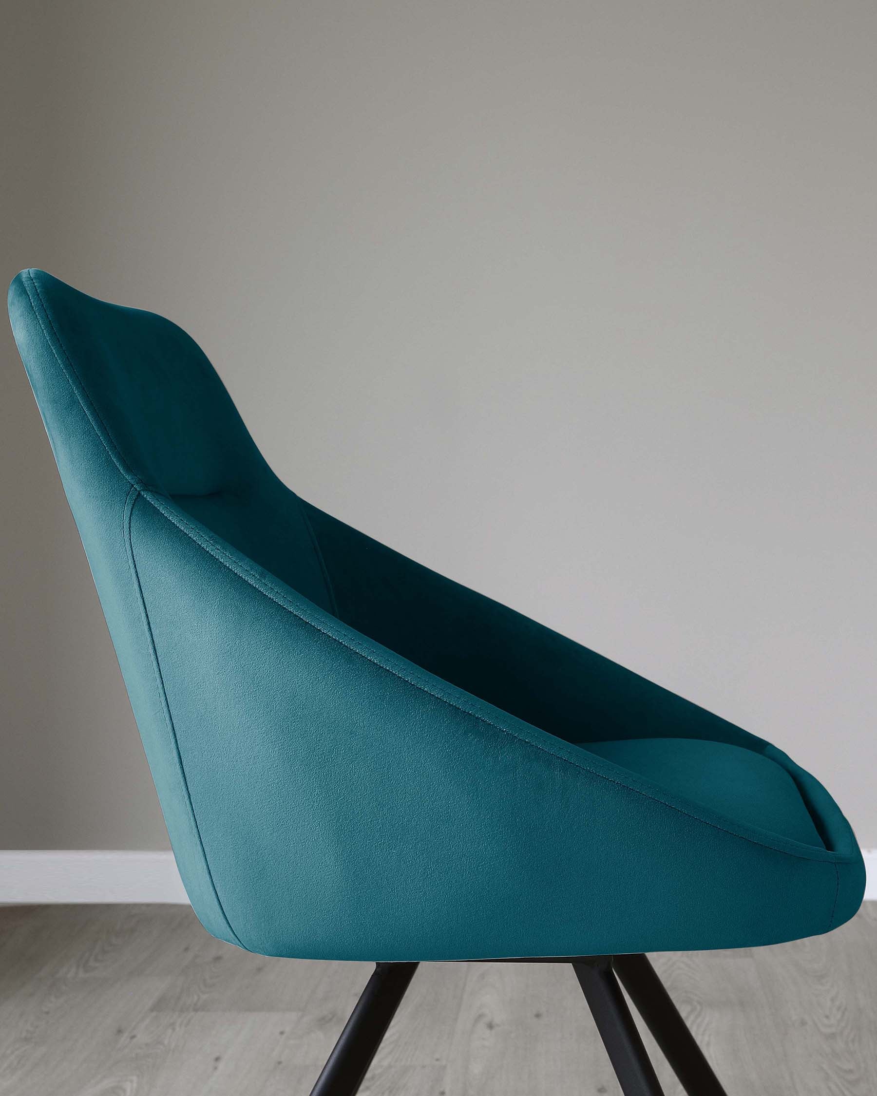 Elegant modern dining chair with teal upholstery and black metal legs on a light wood floor against a neutral grey background.