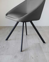 Modern grey upholstered chair with sleek black metal legs on a light wooden floor.