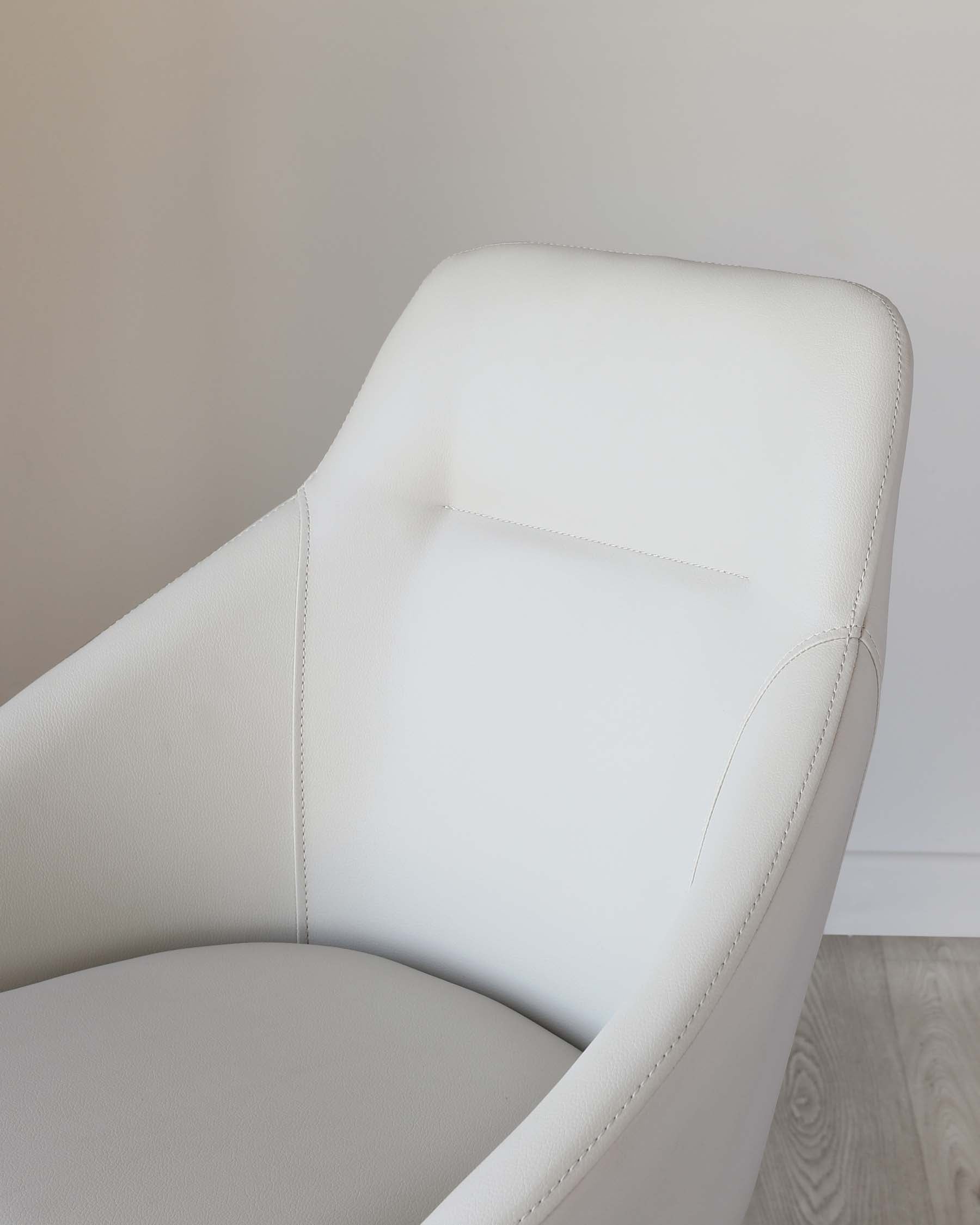 Modern white leather armchair with a curved backrest and an ergonomic seat design, featuring visible stitch detailing.