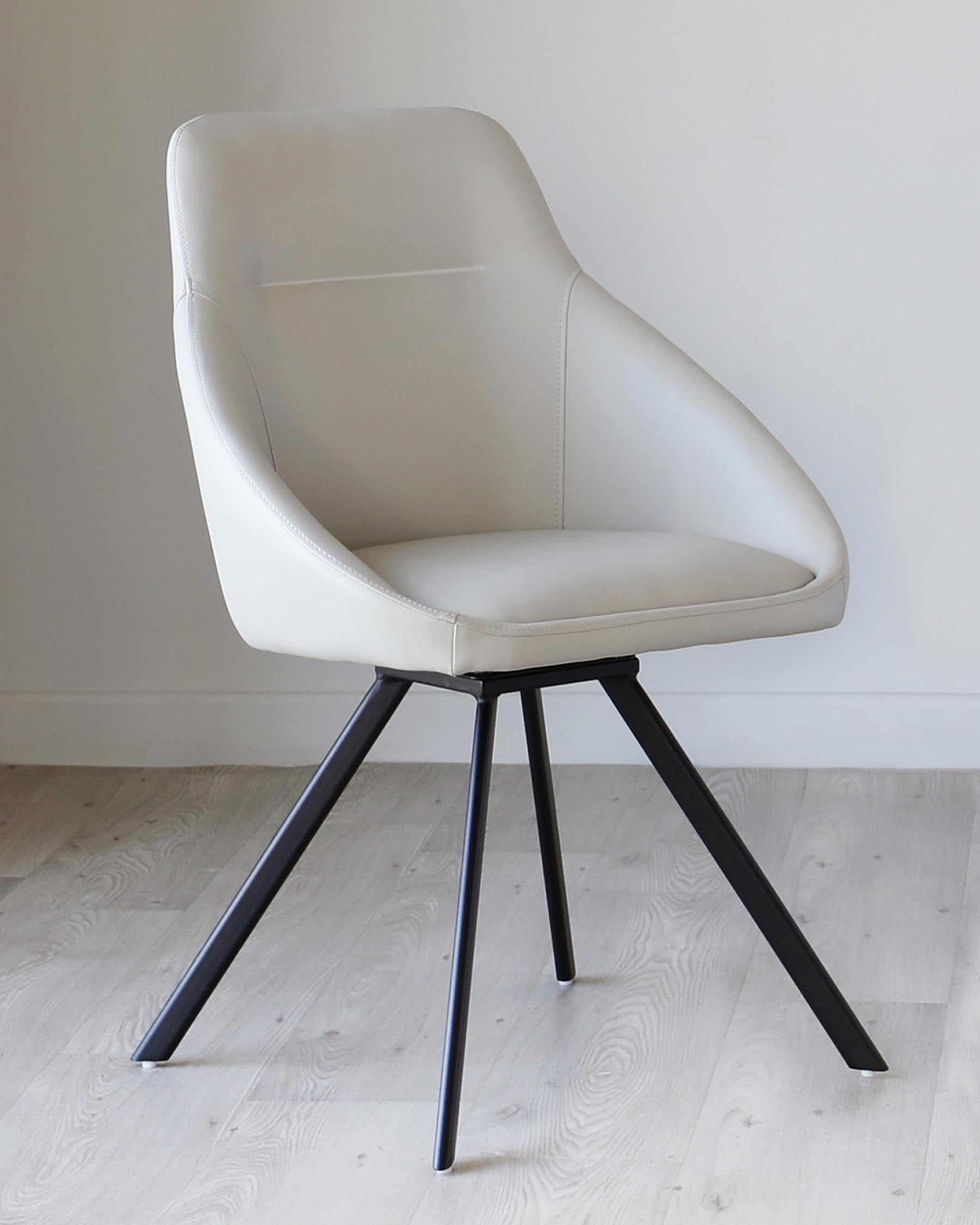 Modern light grey upholstered dining chair with a curved backrest and seat design, featuring distinctive stitching details and set upon four tapered black metal legs.