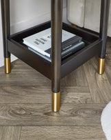 Elegant modern side table with dark wood finish and gold accents on the legs, showcasing a lower shelf with books.